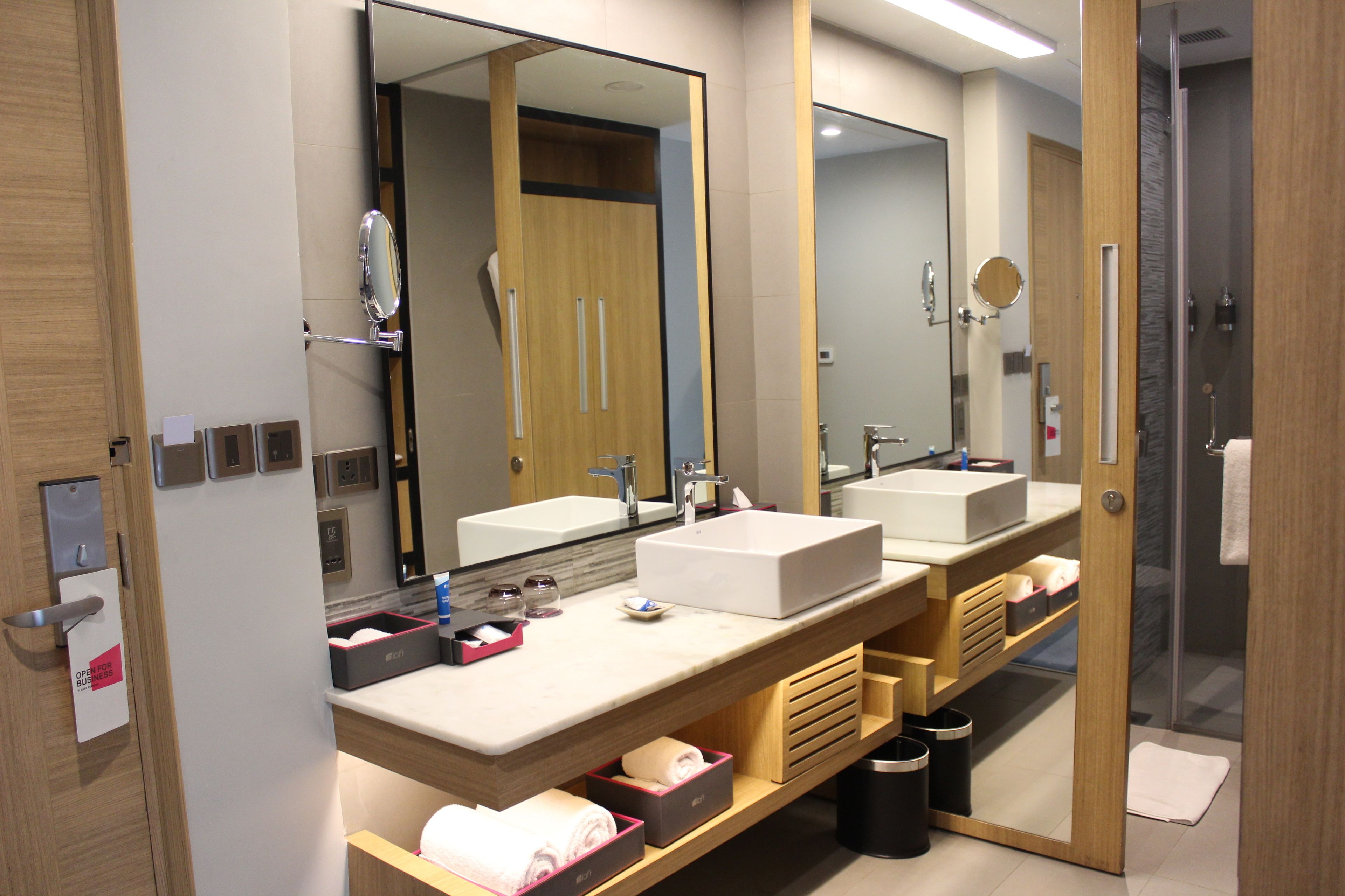 A modern bathroom with two sinks, a large mirror, and a shower area.