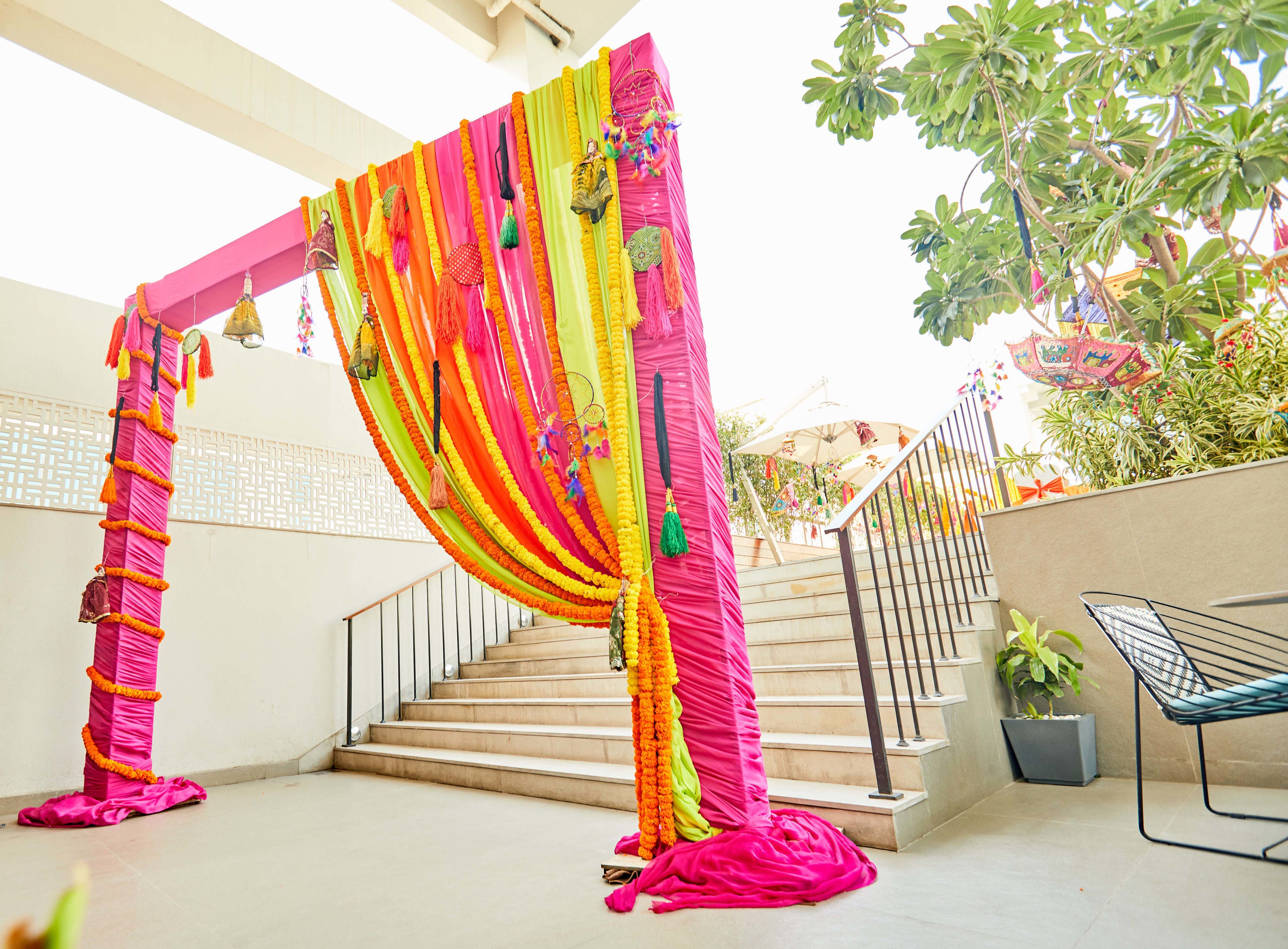 Una escalera con un dosel floral rosa y naranja, una barandilla de metal y una planta en maceta.