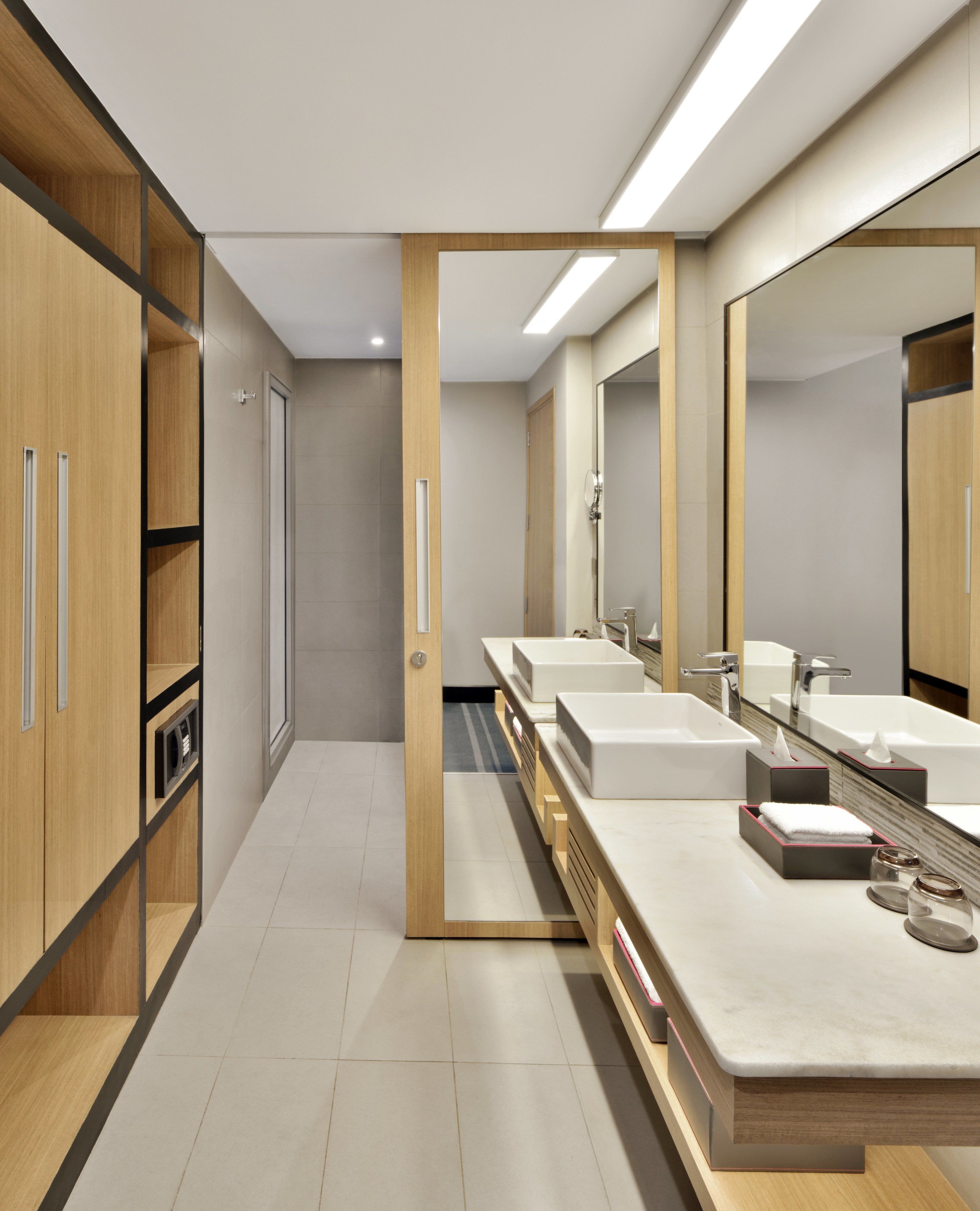 A modern bathroom with three sinks, wooden cabinets, and a large mirror.