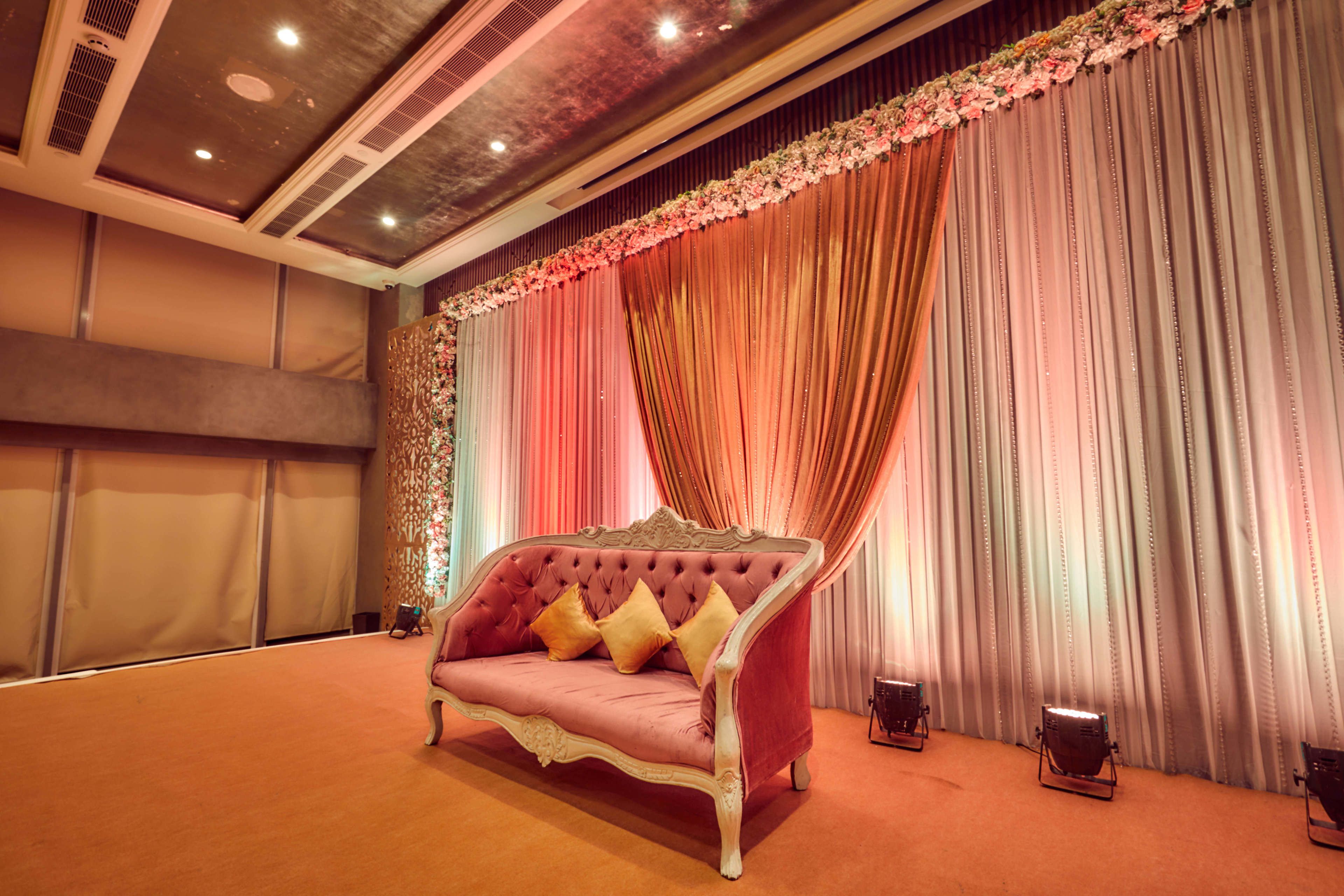 A room with a tufted sofa, draped curtains, and a patterned wall.