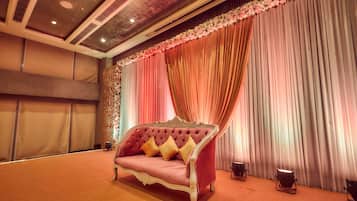 A room with a tufted sofa, draped curtains, and a patterned wall.