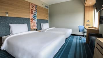 Ein Hotelzimmer mit zwei Betten, einem Schreibtisch, einem Stuhl, einem Fernseher und einer Wand mit dekorativem Holzscheibenmuster.
