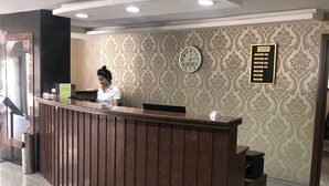A reception desk with a clock and a framed menu board in a hotel lobby. - Kilim Otel (Sanliurfa)