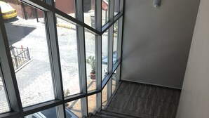 A staircase with a view of the outside through large windows, leading to a landing with a radiator. - Kilim Otel (Sanliurfa)