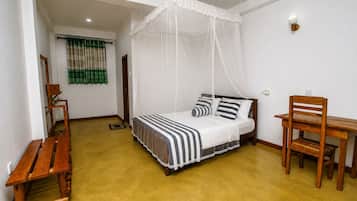 Ein Zimmer mit einem Bett, einem Holztisch, einem Stuhl, einer Bank und einem Vorhangfenster.