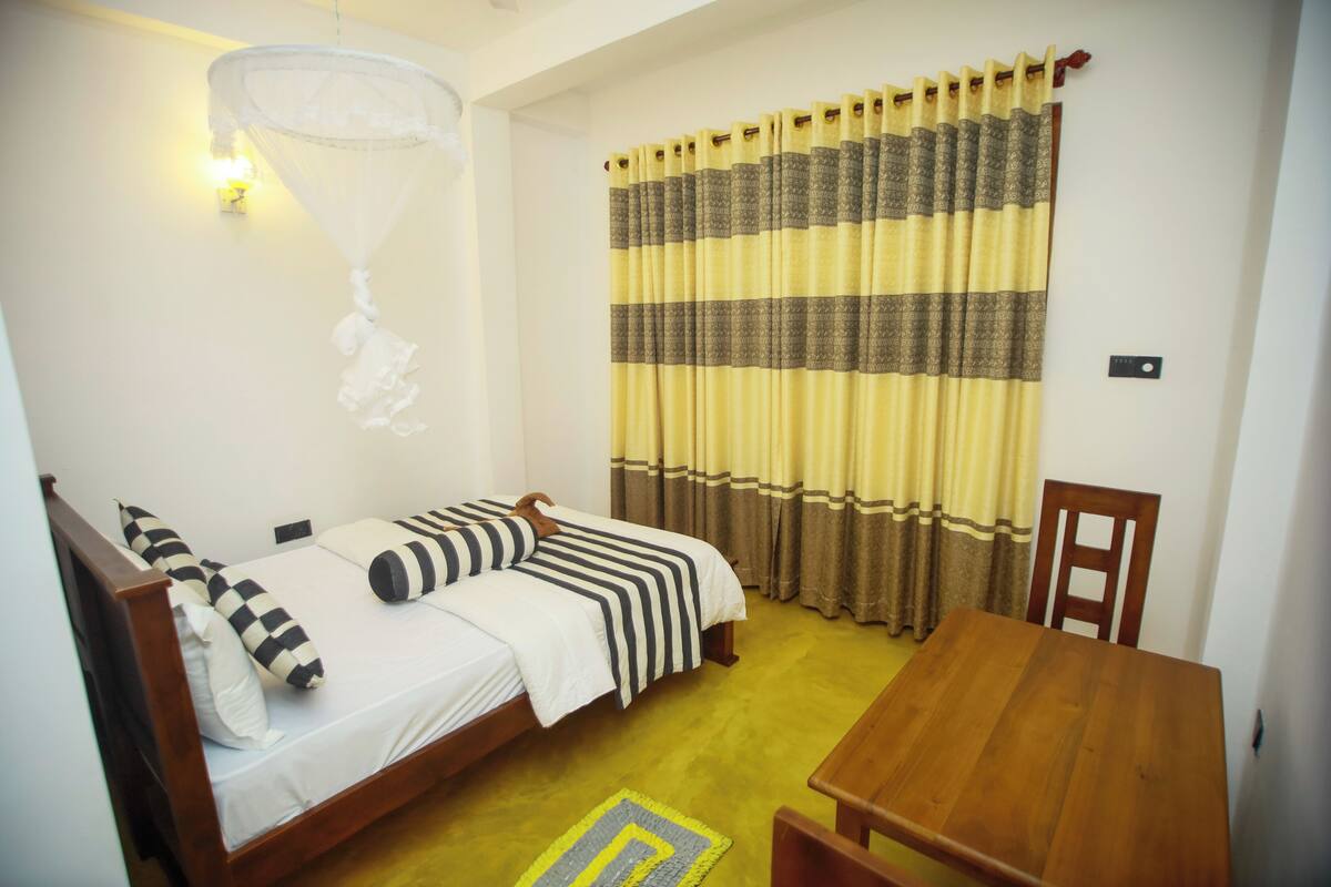 Una habitación con una cama, una mesa de madera y una silla.