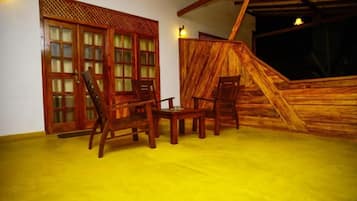 Ein Zimmer mit Holzboden, mehreren Holzsesseln, einem kleinen Tisch und einem Holzbodenverkleidung mit Gitterstruktur.