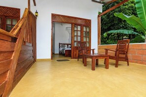 Escada de madeira que leva a um quarto com uma cama, uma mesa de madeira e cadeiras.