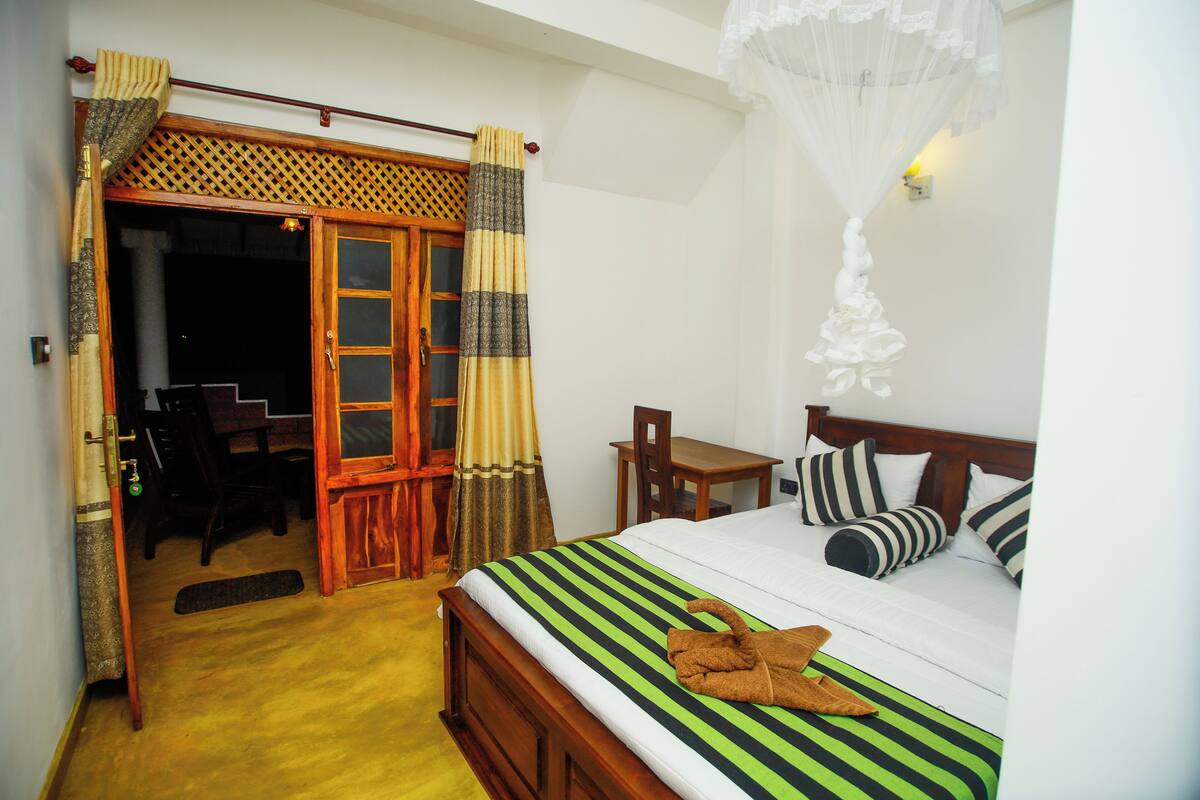 Un dormitorio con cama, cabecera de madera, una mesita y una silla.