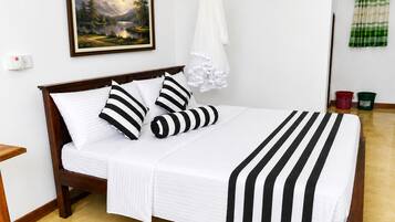 Una cama con una colcha a rayas y almohadas, un cuadro en la pared y un dosel blanco.