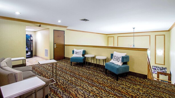 A hotel lobby with a sofa, two armchairs, a small table, and a carpeted floor. - MainStay Suites Madison - Monona (Madison)