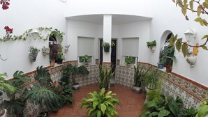 A courtyard with potted plants, tiled walls, and a central drainage grate. - Hostal Andalucia (Nerja)