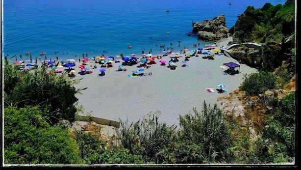 A beach with numerous colorful umbrellas and people enjoying the sun. - Hostal Andalucia (Nerja)