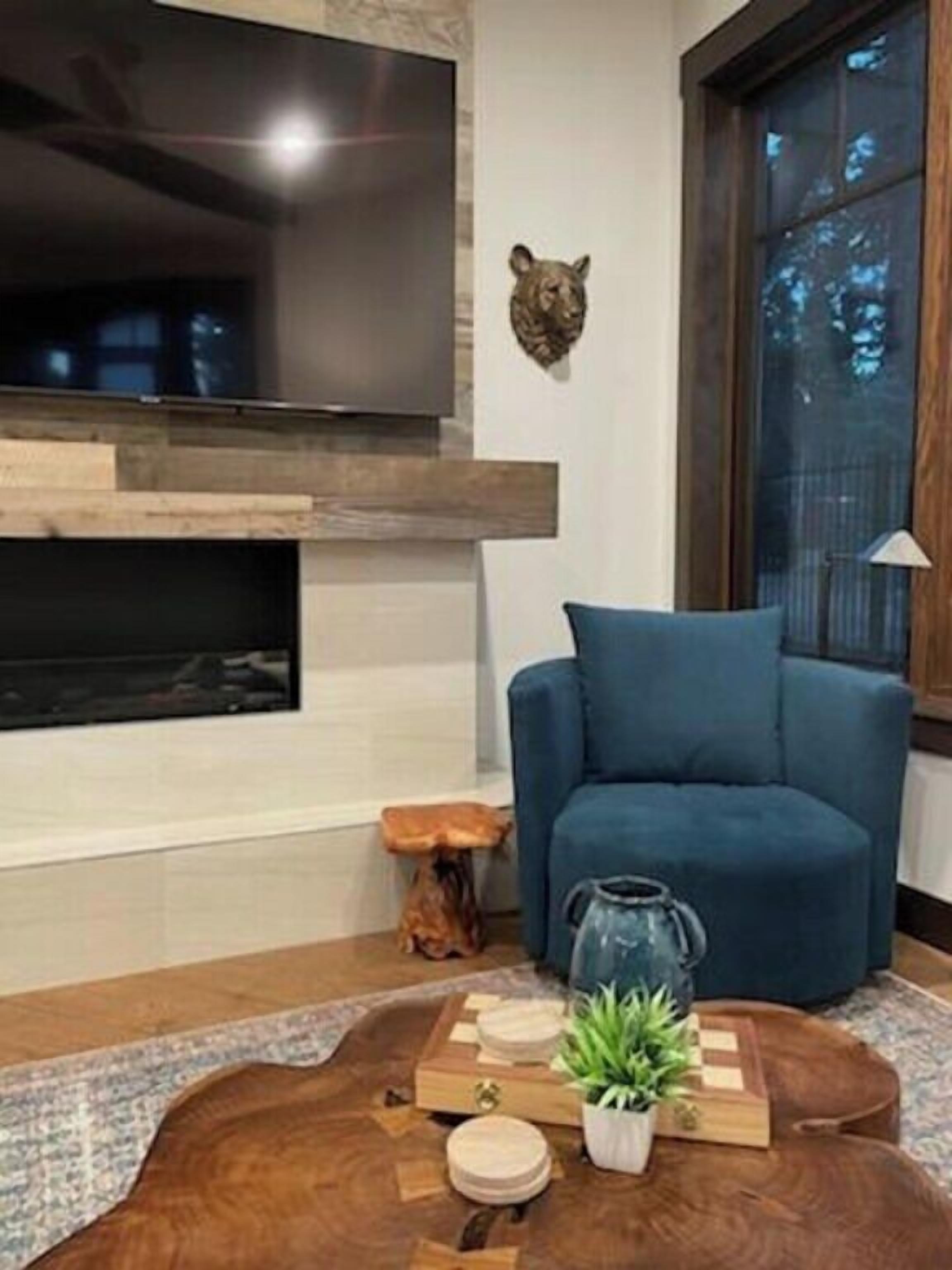 Una sala de estar moderna con un sofá azul, una mesa de centro de madera con una planta y una decoración de oso en la pared.