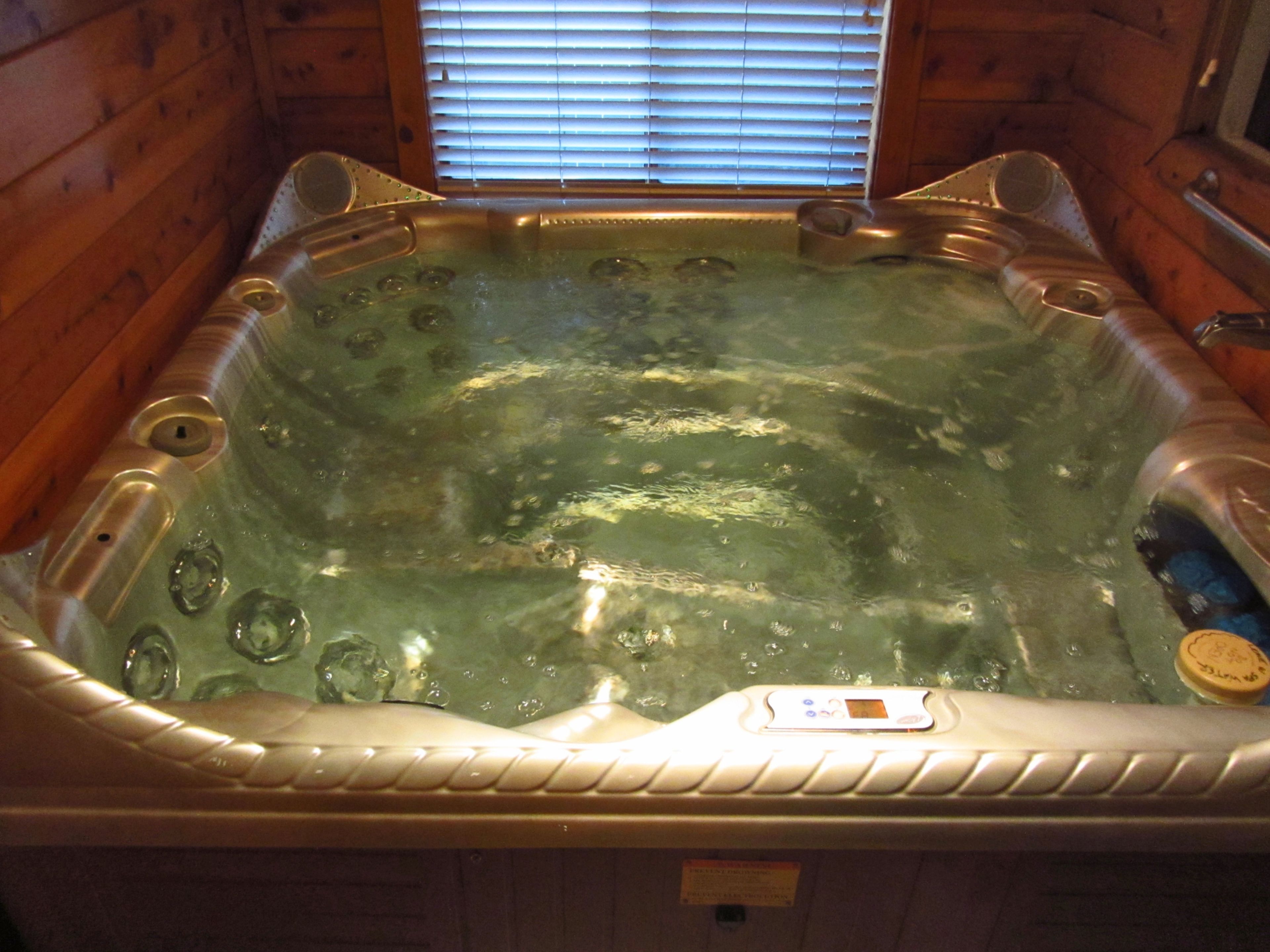 A hot tub in a wooden cabin with a window above it.
