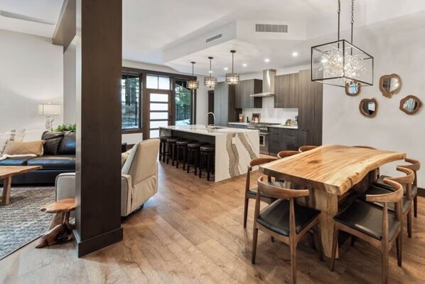 Cocina moderna con una isla central, mesa de comedor de madera y taburetes de bar.