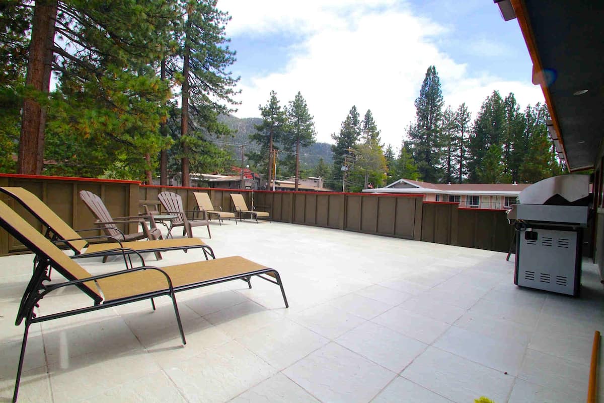 Ein überdachter Patio-Bereich mit Liegestühlen und einem Grill.