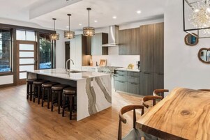 Una cocina moderna con una isla grande, taburetes de bar y una mesa de comedor.