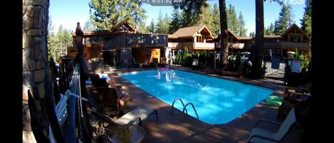 A pool area with lounge chairs and a wooden cabin structure.