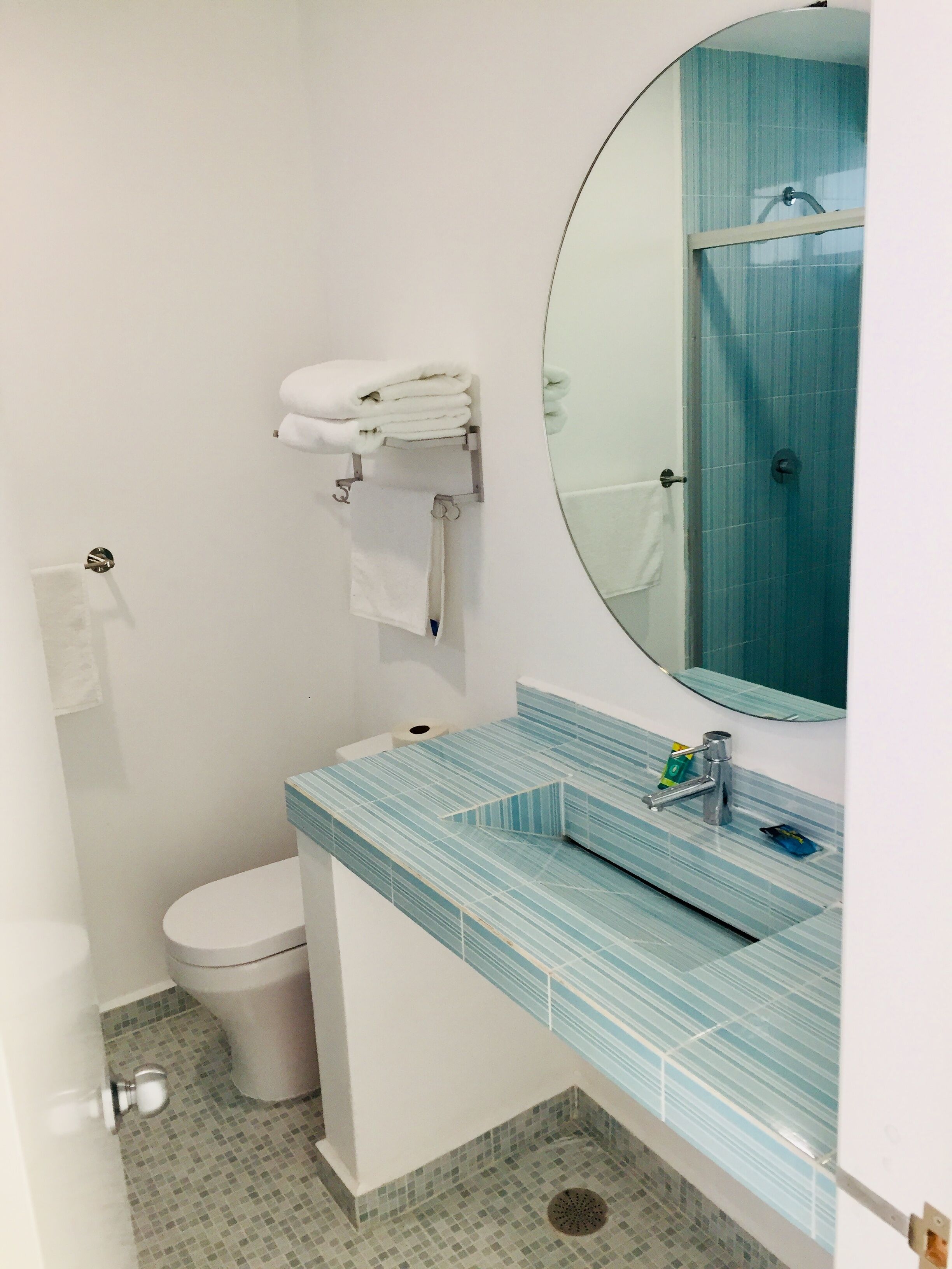 A bathroom with a toilet, a sink with a mirror, and a towel rack.