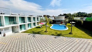 A hotel with a swimming pool, a covered outdoor seating area, and a well-maintained lawn. - Hotel Palmas Cocoyoc (Yautepec)