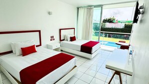 A hotel room with two beds, a small table, and a view of a swimming pool. - Hotel Palmas Cocoyoc (Yautepec)