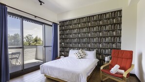 Une chambre à coucher avec un grand lit, un fauteuil rouge et une bibliothèque remplie de livres.