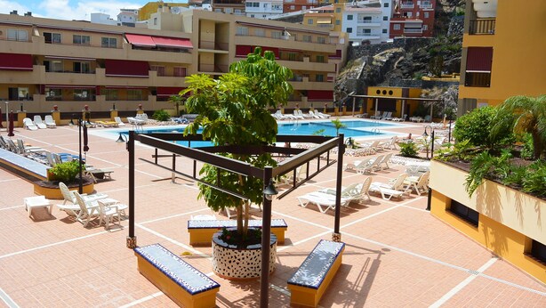 A rooftop pool area with lounge chairs and a central tree. - Olivia Sunbeach (Santiago del Teide)