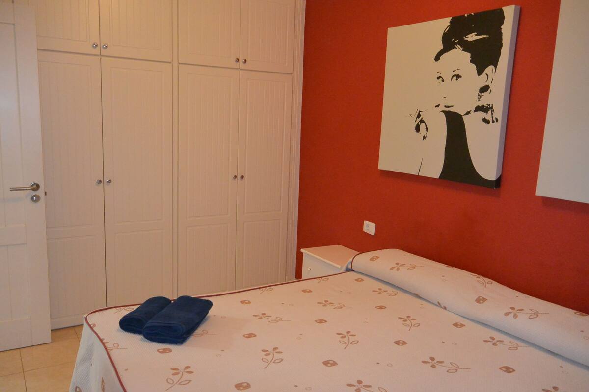 A bedroom with a bed, a wardrobe, and a painting on the wall.