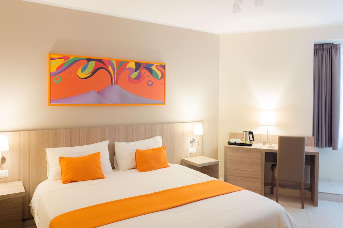 A hotel room with a bed, a desk, and a chair.