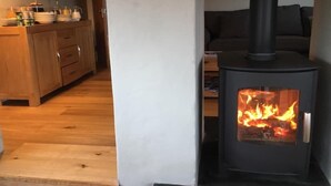 Ein gemütliches Zimmer mit Kaminofen, Holzschränken und einer Couch.