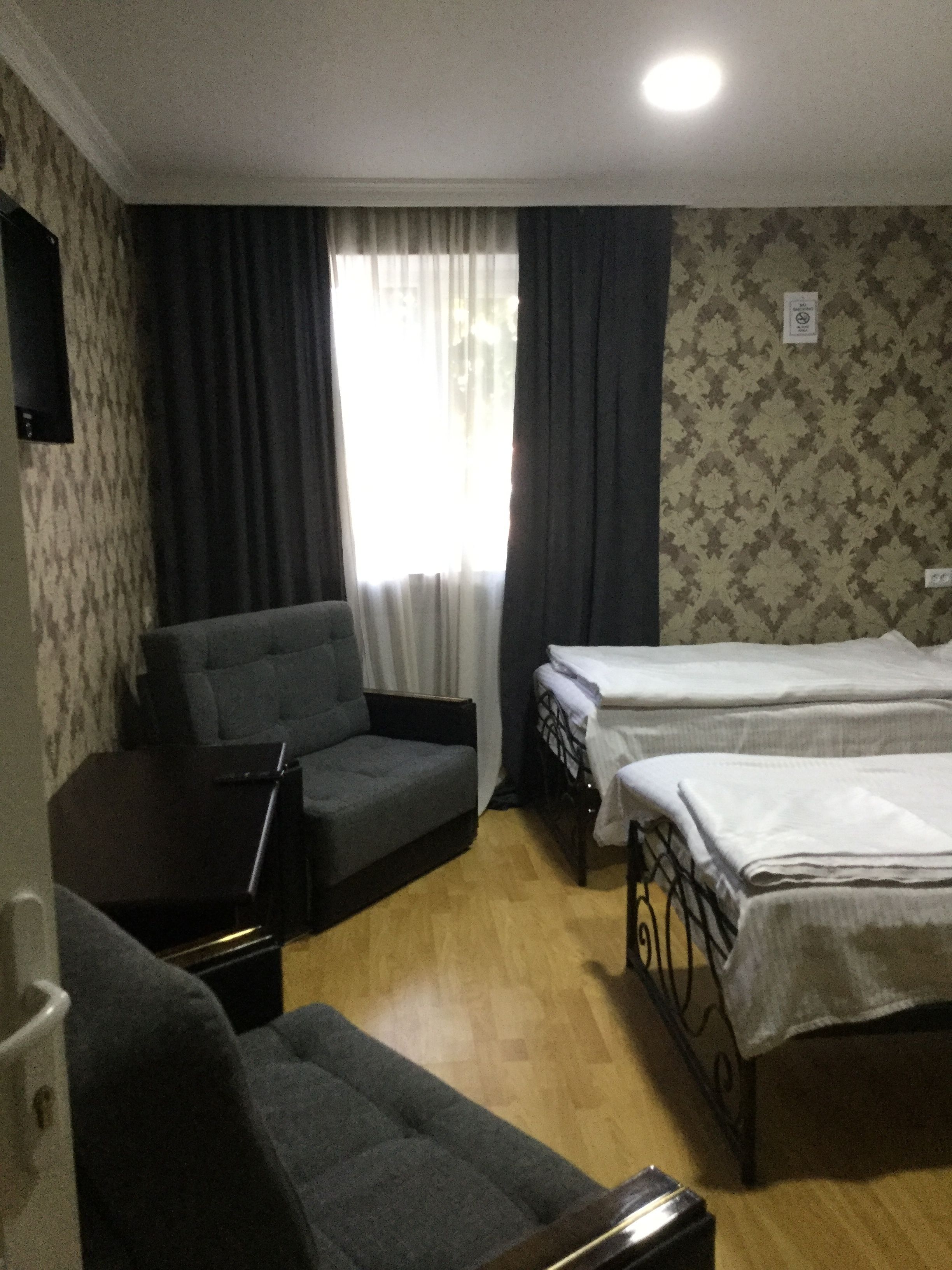 Una habitación con sofá, cama, escritorio y ventana con cortinas.