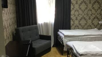 Una habitación con sofá, cama, escritorio y ventana con cortinas.