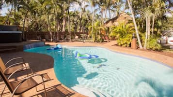 A swimming pool with lounge chairs and inflatable toys.