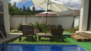 A swimming pool with two lounge chairs and an umbrella. - Casa Oretani (Picon)