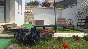 A modern outdoor patio with a pool, surrounded by colorful flowers and two lounge chairs. - Casa Oretani (Picon)