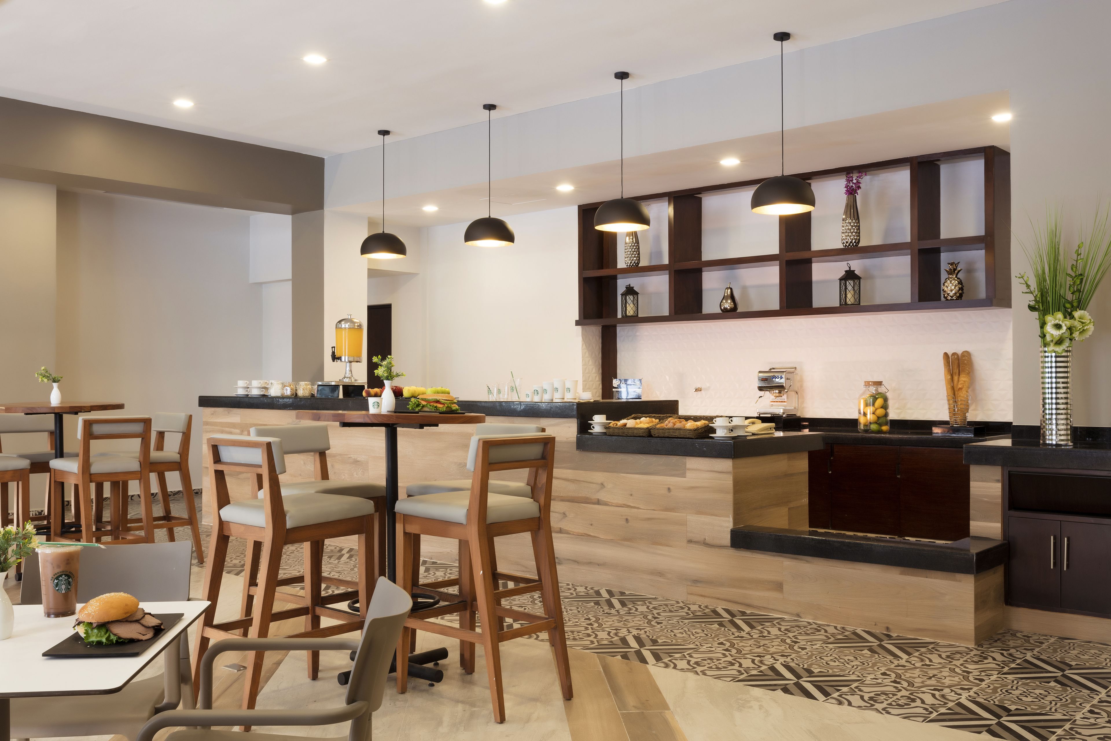 Een modern restaurant met houten stoelen en tafels, hanglampen en een toonbank met diverse producten.