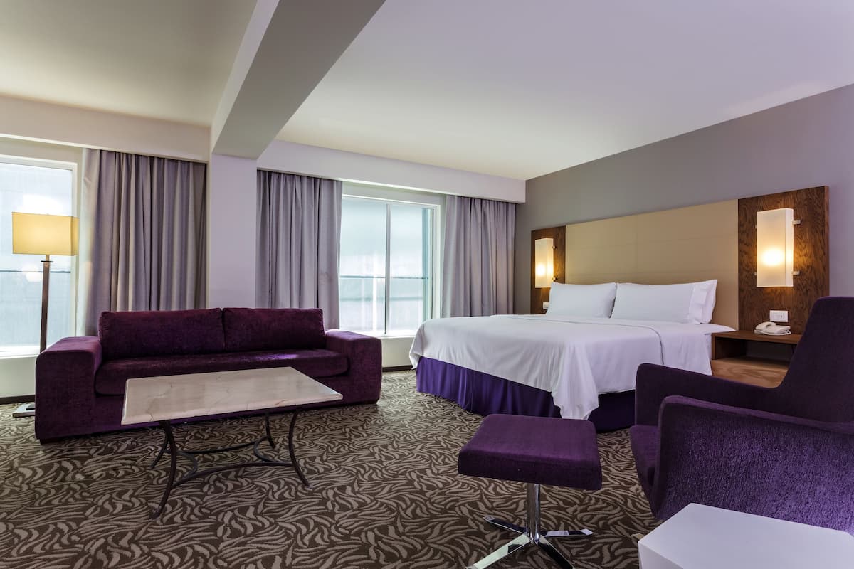 Una habitación de hotel con una cama, un sofá, una silla y una pequeña mesa.