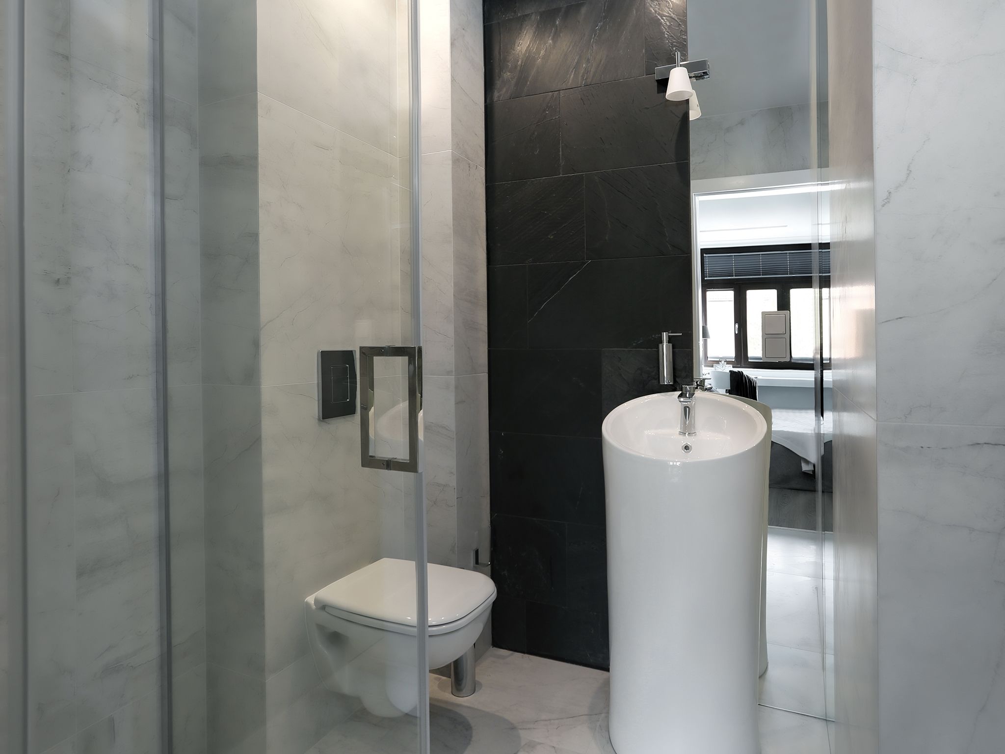 Une salle de bain moderne avec une douche à parois de verre, des toilettes blanches et un grand lavabo blanc.