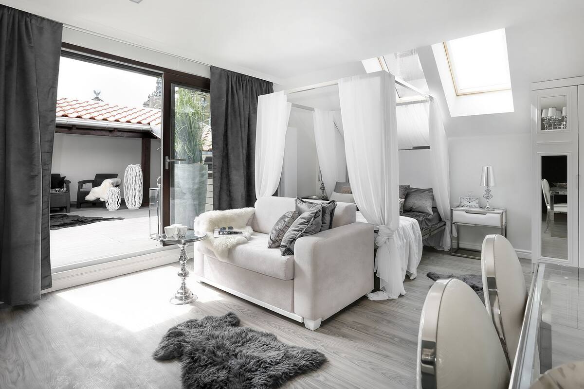 A modern bedroom with a canopy bed, a glass coffee table, and a view of the outdoors.