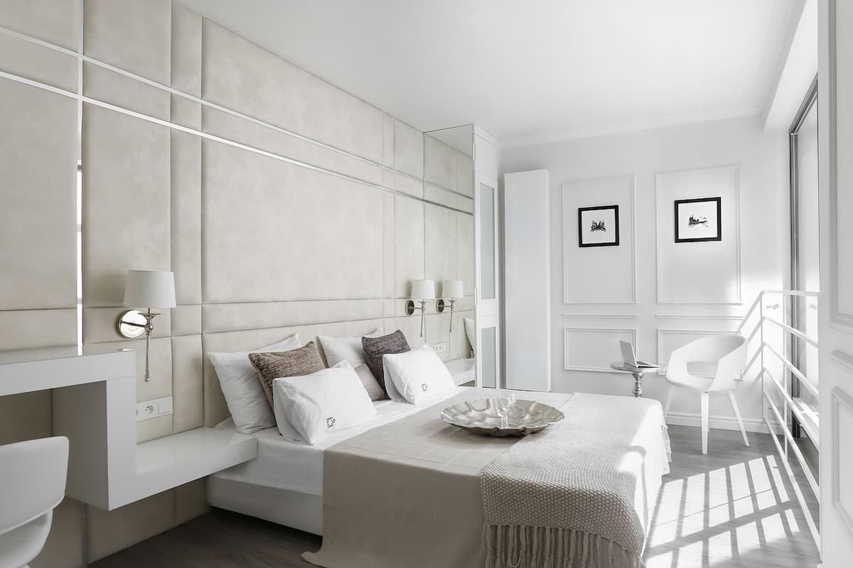 A modern bedroom with a large bed, bedside tables, a chair, and a desk.
