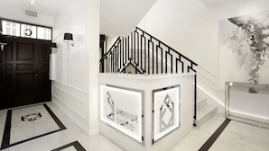 A modern hotel lobby with a staircase, a reception desk, and a wall-mounted artwork. - Sweet Suite Apart (Gdansk)
