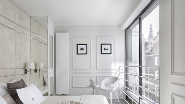 A modern hotel room with a large window, a bed with white linens, a side table, and a decorative tray. - Sweet Suite Apart (Gdansk)