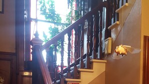 A staircase with a wooden handrail, a fire alarm, and a wall-mounted bell. - Tower Guest House (Stornoway)