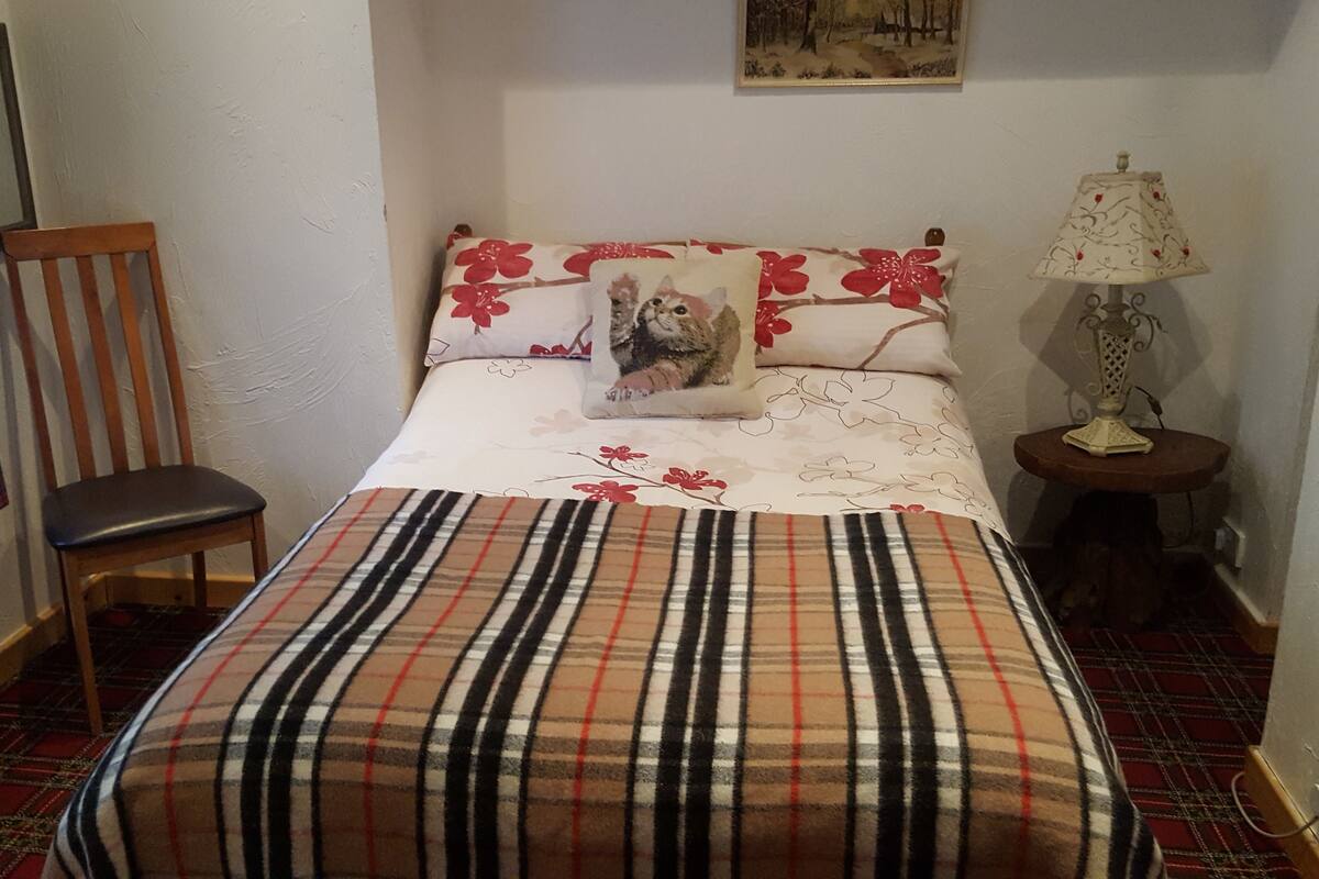 A bedroom with a bed, a chair, a lamp, and a painting on the wall.