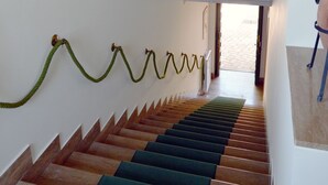 A staircase with alternating dark and light steps, a decorative ceiling with a central skylight, and a green rope barrier. - Antica Villa di Bruto (Tivoli)