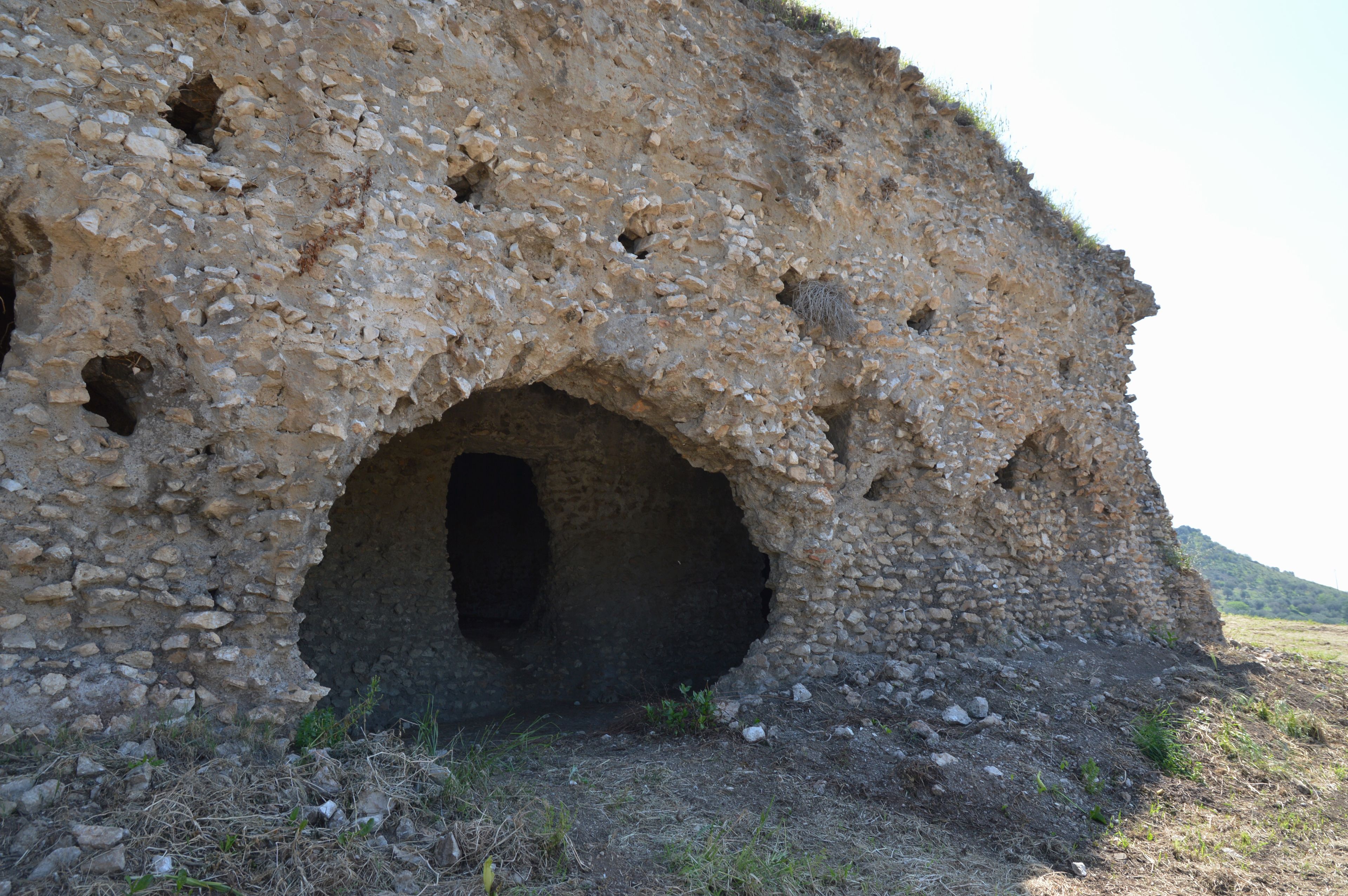 A stone structure with a large central opening and smaller holes around it.