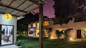 Une vue nocturne d’un quartier résidentiel, avec un patio couvert, des sièges d’extérieur et une entrée bien éclairée.