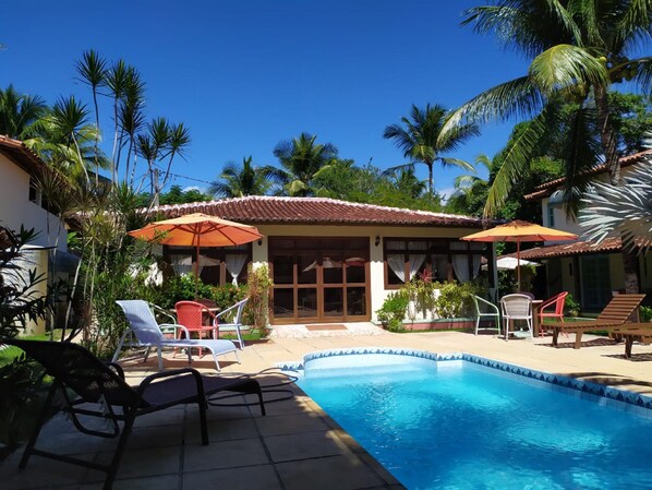 Una piscina al aire libre, sombrillas, sillones reclinables de piscina