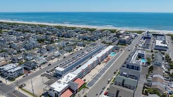 An aerial view of a coastal town with a marina, residential buildings, and a hotel with a swimming pool.